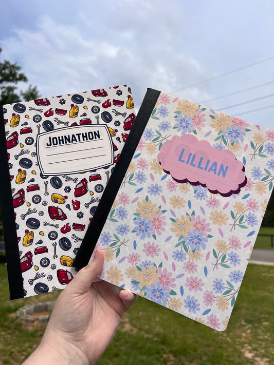 Two notebooks with different designs held by a hand outdoors.