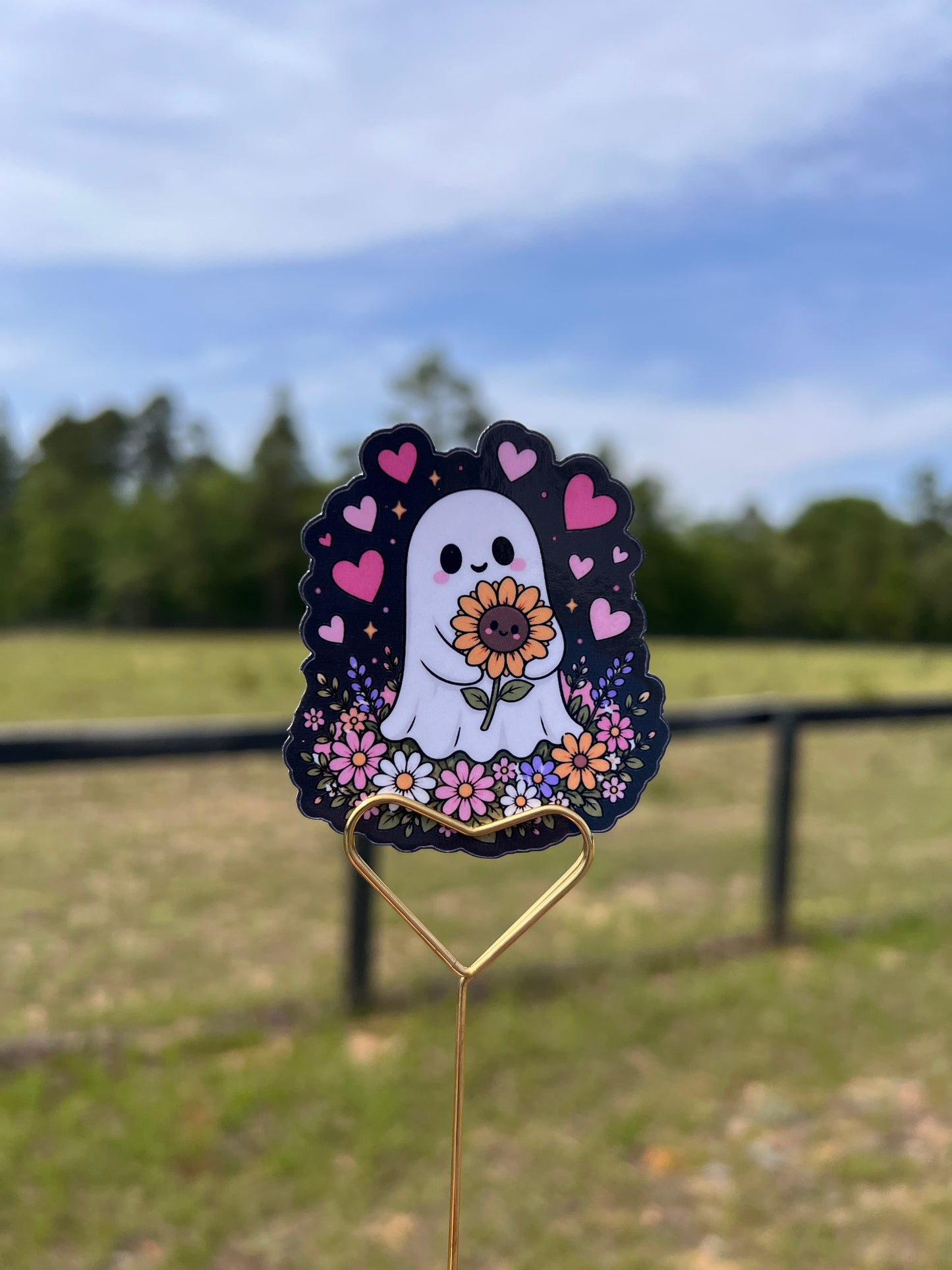 Decorative sticker with a ghost holding a sunflower against a natural background