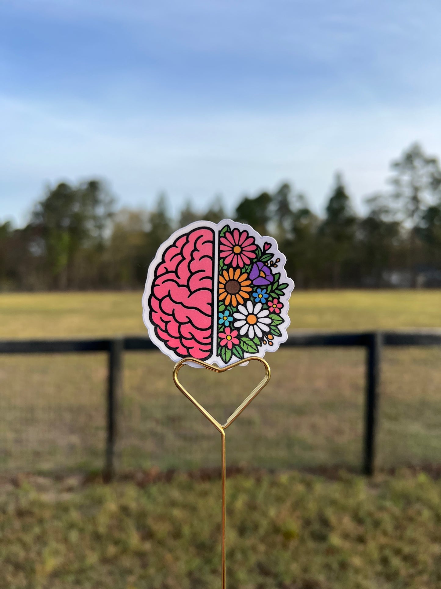 Decorative sticker of a brain with flowers on a hair clip against a blurred natural background