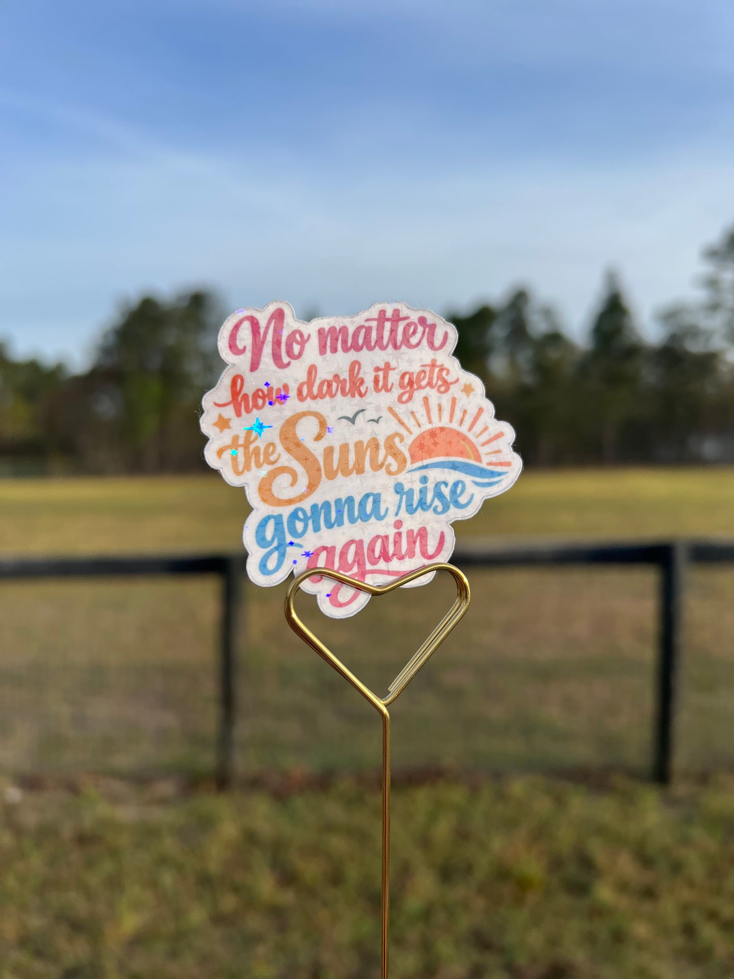 Decorative sticker with motivational quote on a wire against a blurred natural background