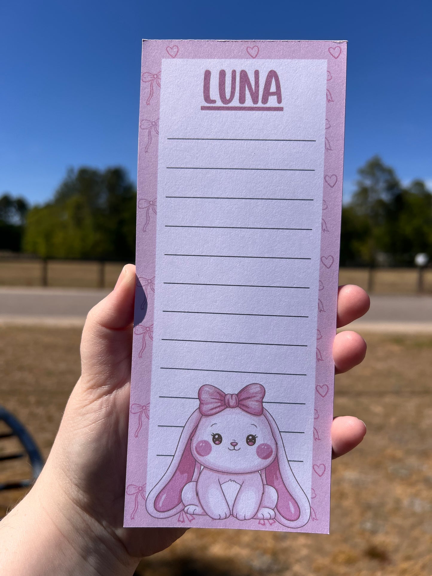 Notepad with 'Luna' design held by a hand against a blurred outdoor background