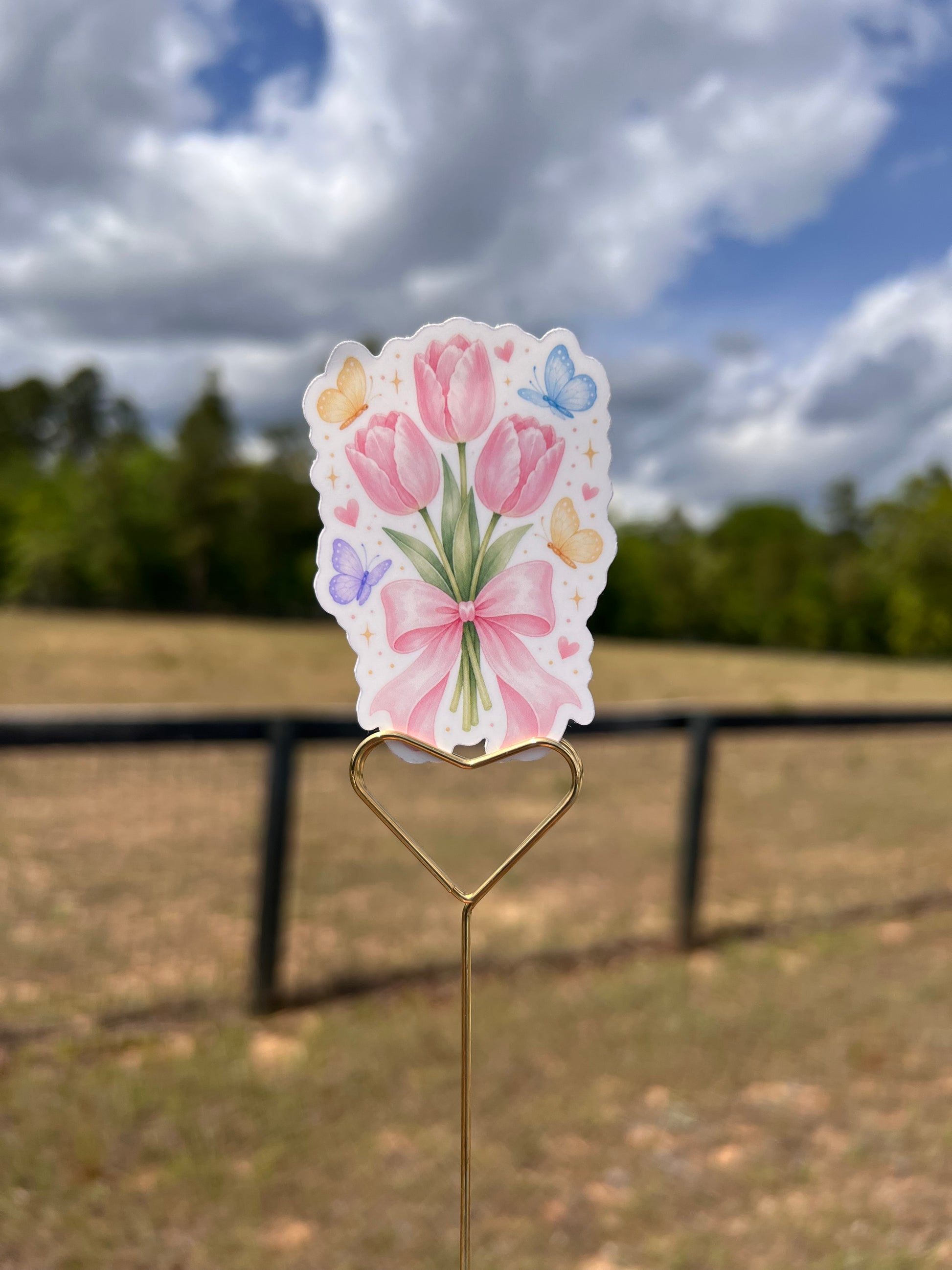 Decorative paper clip with floral design against a blurred outdoor background