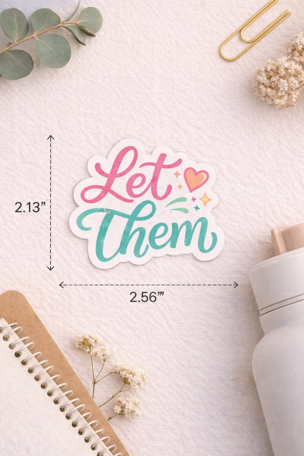 Sticker with 'Let Them' text on a light surface with decorative elements