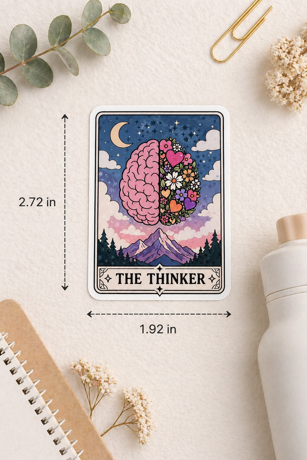 Card featuring 'The Thinker' with brain and nature elements on a light surface with measurements and stationery items.